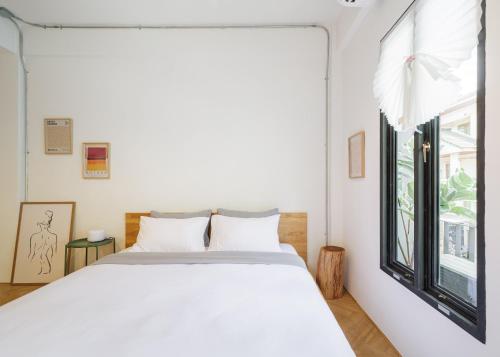a bedroom with a white bed and a window at Wabisabi Bangkok 3 MIN To Train Station in Bangkok