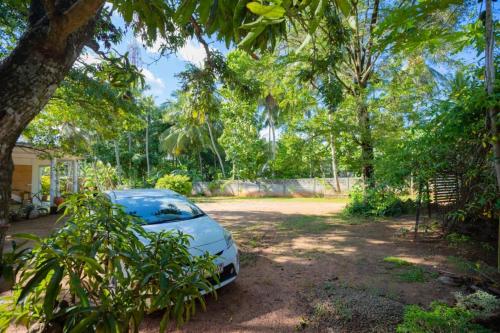 a car parked in front of a yard with trees at Hotel Varsha in Kekirawa