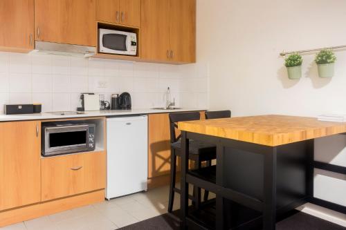 パースにあるCosy & Central Studio APT in The Heart of Perthのキッチン(木製テーブル、白い冷蔵庫付)
