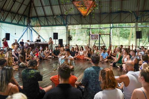 a crowd of people sitting on the floor watching a man on a stage at Pyramid Yoga Koh Phangan in Koh Phangan
