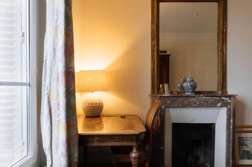 Cette chambre comprend une table avec une lampe et un miroir. dans l'établissement Stylishly Decorated 2BD Apartment Montmatre!, à Paris