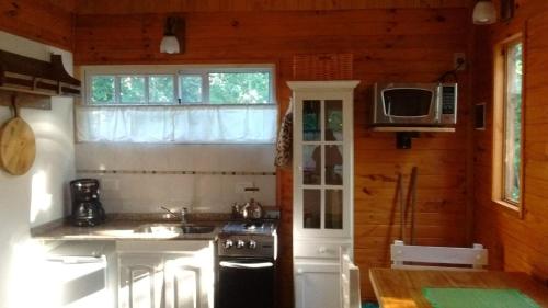 a small kitchen with a stove and a microwave at Cabañas Pa ke mas in Punta Indio