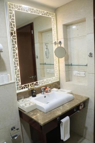 a bathroom with a sink and a mirror at SkyCity Hotel Gurgaon in Gurgaon