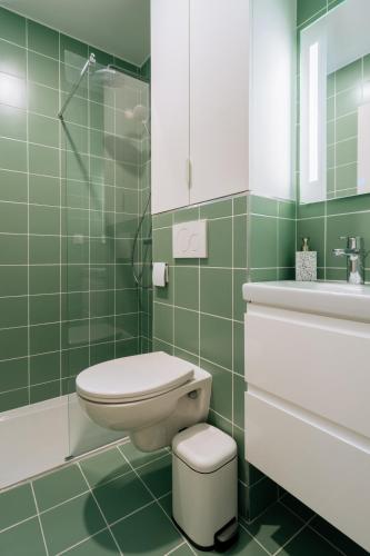 La salle de bains est pourvue de carrelage vert, de toilettes et d'un lavabo. dans l'établissement Stunning 1 Bedroom Apartment in Paris, à Paris