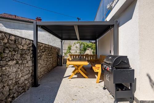 eine Terrasse mit einem Grill und einem Holztisch in der Unterkunft Pool House Old Town - Happy Rentals in Novi Vinodolski