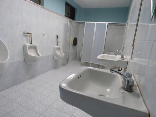 a bathroom with three urinals and a sink and toilets at Casa Centro Historico Hostel in Oaxaca City