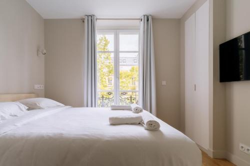une chambre avec un lit blanc avec une fenêtre dans l'établissement Relaxing Studio Apartment in the Heart of Paris, à Paris
