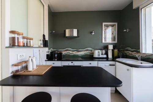 - une cuisine avec un plan de travail noir et un évier dans l'établissement Breathtaking 2BD Apartment Roof-top Patio 19e!, à Paris