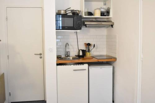 une petite cuisine avec des armoires blanches et un micro-ondes dans l'établissement Functional Studio In Paris, à Paris