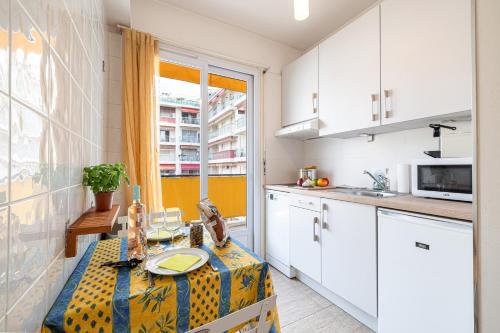 une cuisine avec des placards blancs et une table avec une plaque de cuisson. dans l'établissement Studio Mogador - Close to the beach - Happy Rentals, à Nice