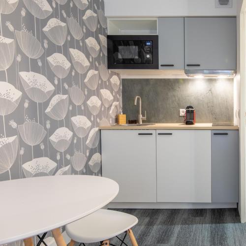une cuisine avec des armoires blanches et une table dans l'établissement New Studio Near Bois de Vincennes, à Paris