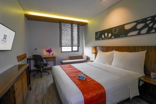 a hotel room with a large bed and a desk at BATIQA Hotel Palembang in Palembang