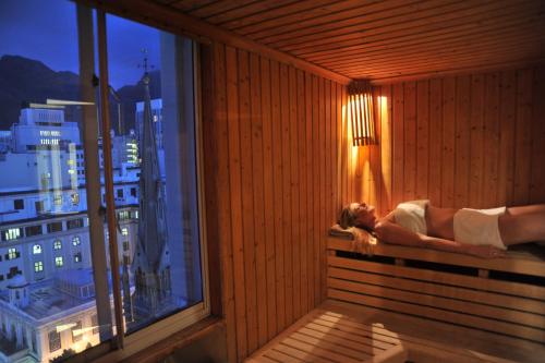 a woman laying in a sauna with a view of a city at ONOMO Hotel Cape Town – Inn On The Square in Cape Town