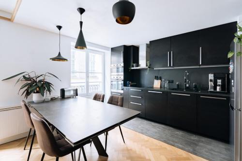une cuisine avec des armoires noires, une table et des chaises dans l'établissement Le Marais - Modern design apartment, à Paris