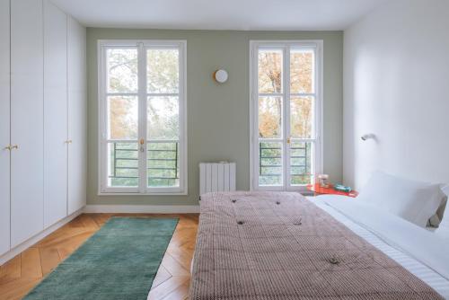 une chambre avec un grand lit et deux fenêtres dans l'établissement Modern Rustic-style Apartment 7th arrondissement!, à Paris