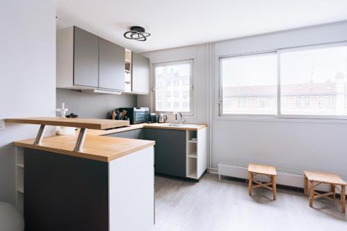 - une cuisine avec un comptoir, 2 chaises et 2 fenêtres dans l'établissement Exuberant 1BD Apartment near Canal Saint-Martin!, à Paris