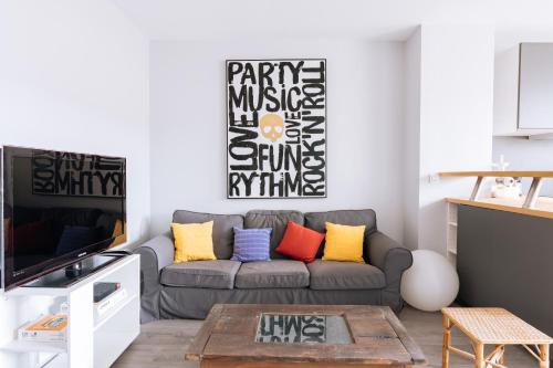 - un salon avec un canapé gris et des oreillers colorés dans l'établissement Exuberant 1BD Apartment near Canal Saint-Martin!, à Paris