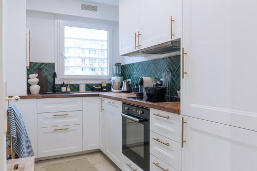une cuisine avec des armoires blanches et une fenêtre dans l'établissement Beautiful 1BD Apartment Issy-les-Moulineaux!, à Issy-les-Moulineaux