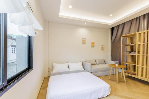 a room with a bed and a couch and a window at Wabisabi Bangkok 3 MIN To Train Station in Bangkok