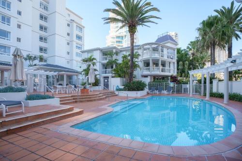 a swimming pool at a resort with palm trees and buildings at La Grande Apartments in Gold Coast