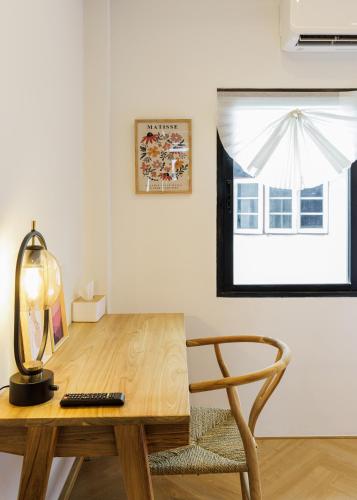 a wooden desk with a chair and a window at Wabisabi Bangkok 3 MIN To Train Station in Bangkok