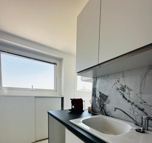 une cuisine blanche avec un évier et une fenêtre dans l'établissement La plage, à Marseille