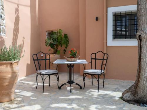 a patio with a table and chairs and plants at St-Ten Stone Built Village in Áyioi Dhéka