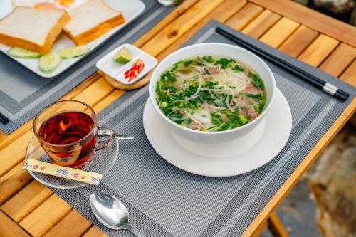 a bowl of soup on a table with a plate of food at Muong Hoa Eco Villa in Sa Pa