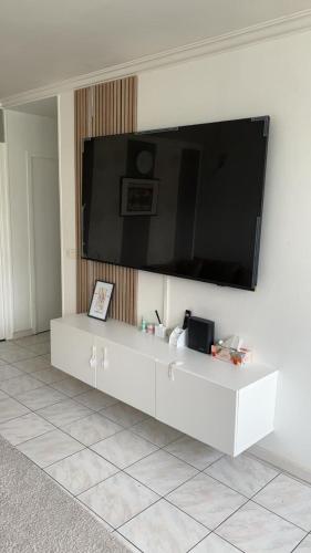 - un centre de divertissement blanc avec une grande télévision murale dans l'établissement Magnifique appartement, à Stains