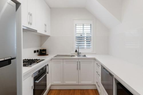 a white kitchen with white cabinets and a sink at Harbour View Terrace House In The Heart Of The Rocks in Sydney