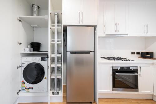 a kitchen with a refrigerator and a washer and dryer at Harbour View Terrace House In The Heart Of The Rocks in Sydney