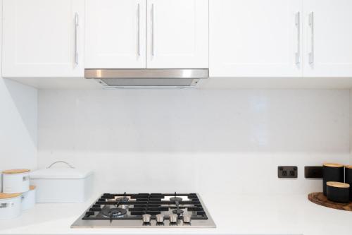 a kitchen with white cabinets and a stove top at Harbour View Terrace House In The Heart Of The Rocks in Sydney