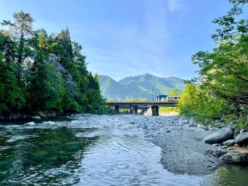 a river with a bridge and mountains in the background at Spruce Cottage in Yuzawa