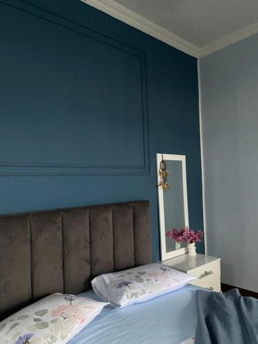 a bedroom with a blue wall with a bed and a mirror at Horizon Hills - ჰორიზონ ჰილს in Kvariati