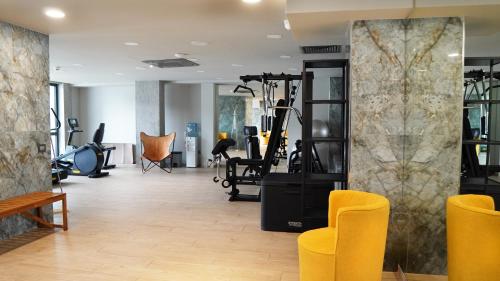a gym with yellow chairs and exercise equipment at Aniroc Signature Hotel in Arad
