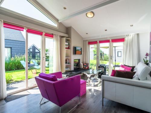 a living room with purple chairs and windows at Modern Holiday Home in Kattendijke with a Garden in Kattendijke