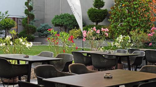 an outdoor patio with tables and chairs and flowers at Aniroc Signature Hotel in Arad