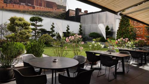a patio with tables and chairs and a garden at Aniroc Signature Hotel in Arad