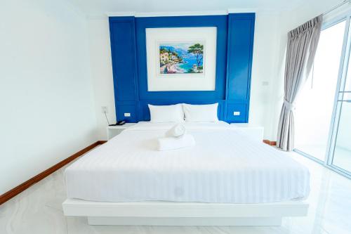 a white bed in a room with a blue wall at Marble Arch De Loei Hotel in Loei