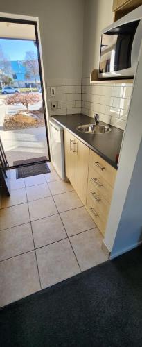 a small kitchen with a sink and a window at ASURE Central Gold Motel Cromwell in Cromwell