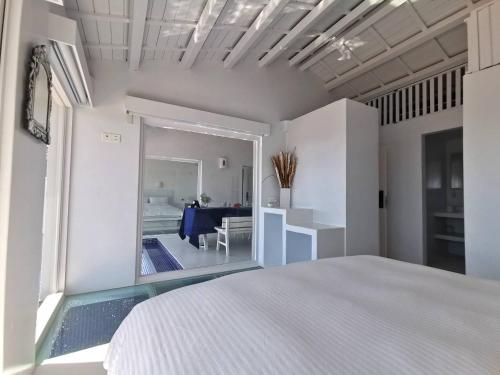 a white bedroom with a bed and a dining room at Ample Villa 小希臘民宿 in Ruifang