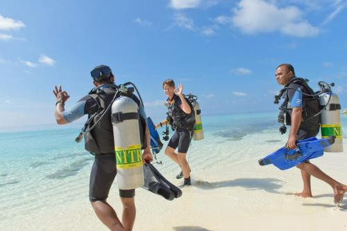 a group of people walking on the beach at Eriyadu Island Resort in Reethi Rah