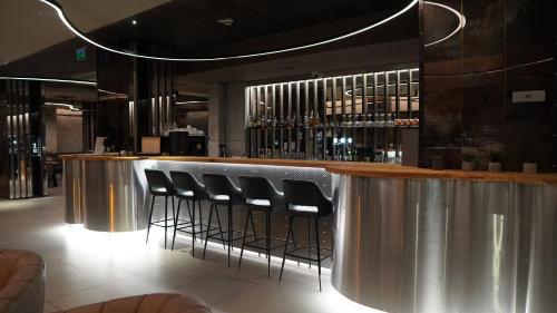 a bar with a row of stools in a restaurant at Aniroc Signature Hotel in Arad