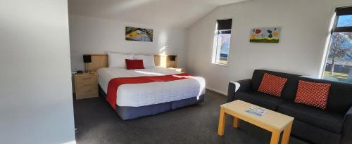 a small bedroom with a bed and a couch at ASURE Central Gold Motel Cromwell in Cromwell