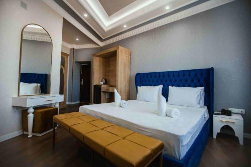 a bedroom with a large bed with a blue headboard and a mirror at Antalya Grand Palace Hotel in Urganch