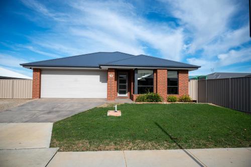 a red brick house with a white garage at Grevillea House in Echuca
