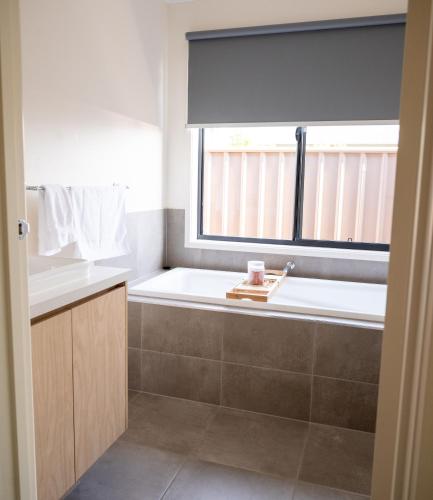 a bathroom with a bath tub and a window at Grevillea House in Echuca