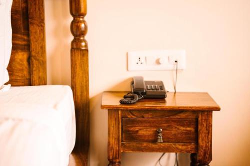 a telephone on a wooden table next to a bed at RajBagh by Aaryam in Sawāi Mādhopur