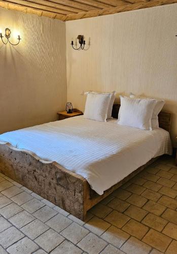 une chambre avec un grand lit avec des draps et des oreillers blancs dans l'établissement La Petite Marguerite, à Les Fourgs