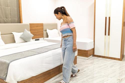 a woman walking in a bedroom next to a bed at Daksh Eden Greenz -A Luxury Resort in Sasan Gir in Sasan Gir